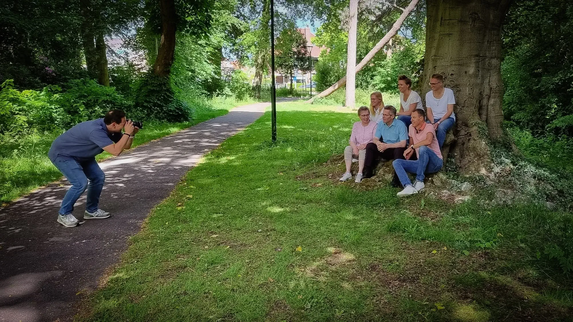 Stefan Segers fotografeert een groep van zes mensen onder een grote boom in een park