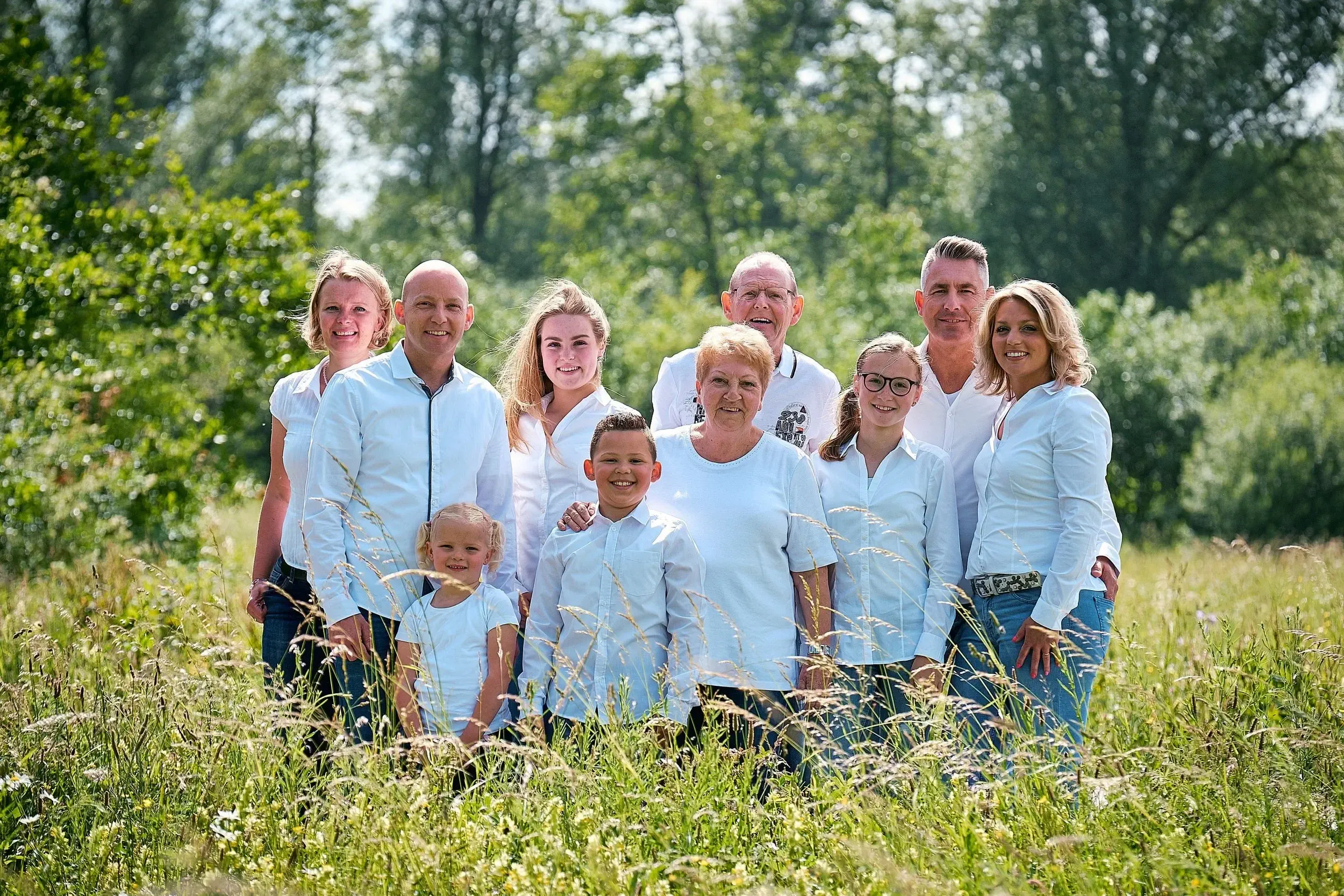 Familie fotoshoot in het park midden op de dag. Door de zon achter de groep te houden hoeft niemand de ogen niet te knijpen en krijg je zacht licht op het gezicht.